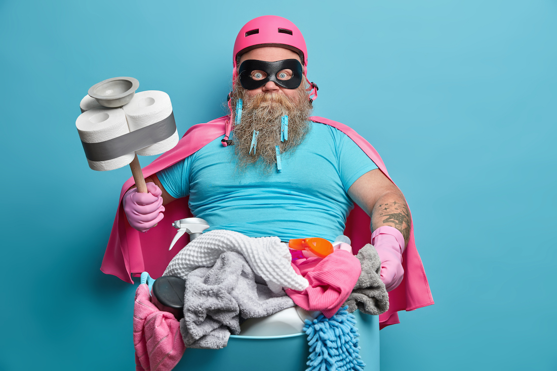 Everyday routine and housekeeping concept. Bearded stout man janitor does laundry at home pose with basin full of dirty clothes holds plunger wrapped with toilet paper 