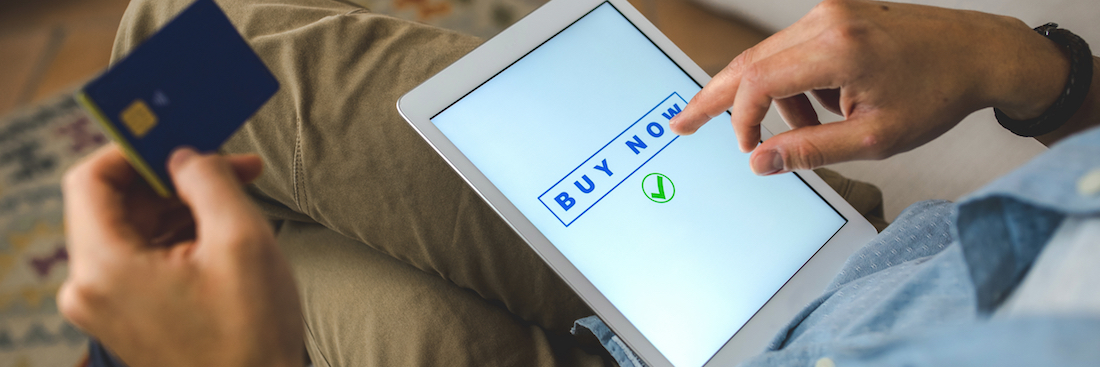 Man doing online shopping using a tablet sitting on the sofa, internet payment with a credit card