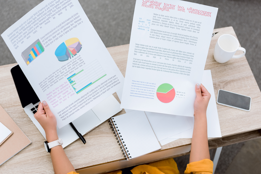 cropped shot of young woman working with white papers at office