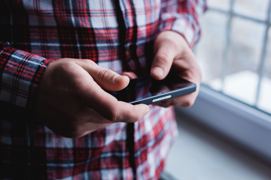 A man is using a smartphone. Modern mobile phone in hand.