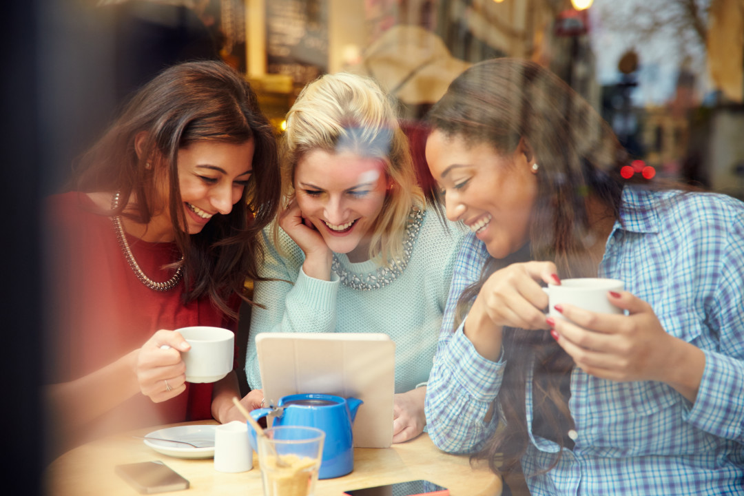 Group Of Female Friends In Cafe Using Digital tablet